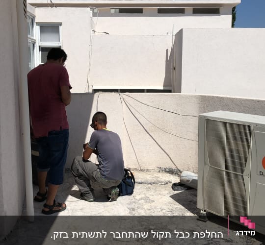טכנאי עובד על מערכת מיזוג אוויר על גג